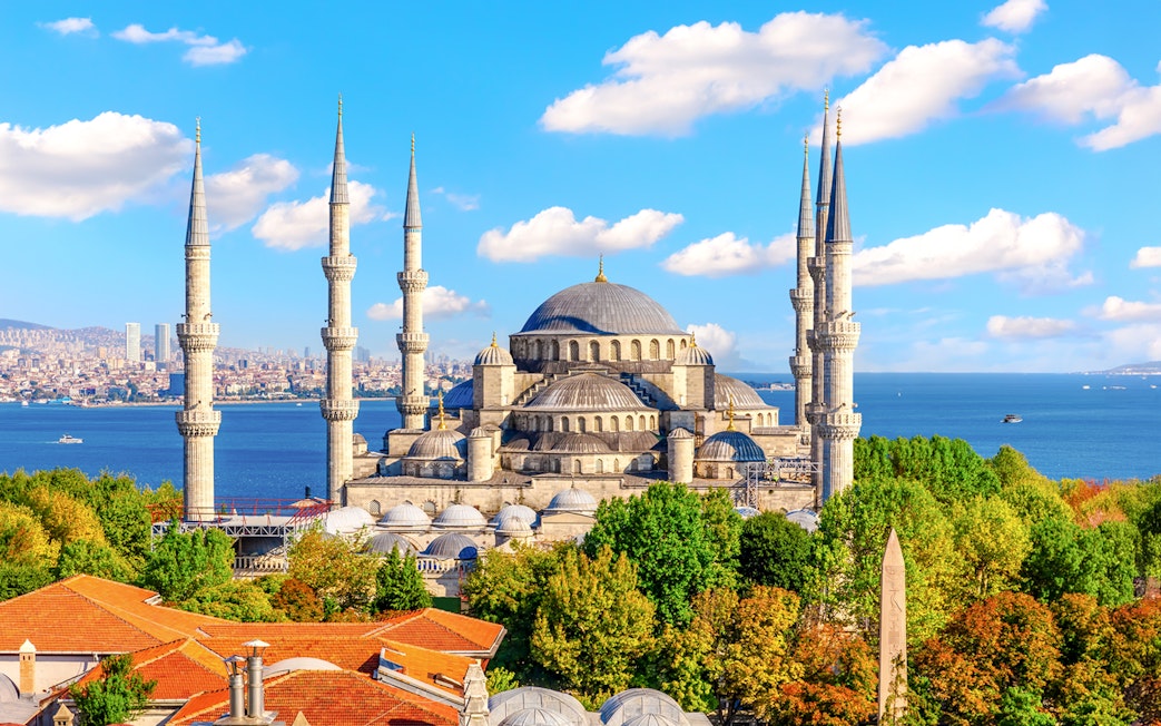 Blue Mosque exterior with minarets and domes, Istanbul skyline and Bosphorus in background.