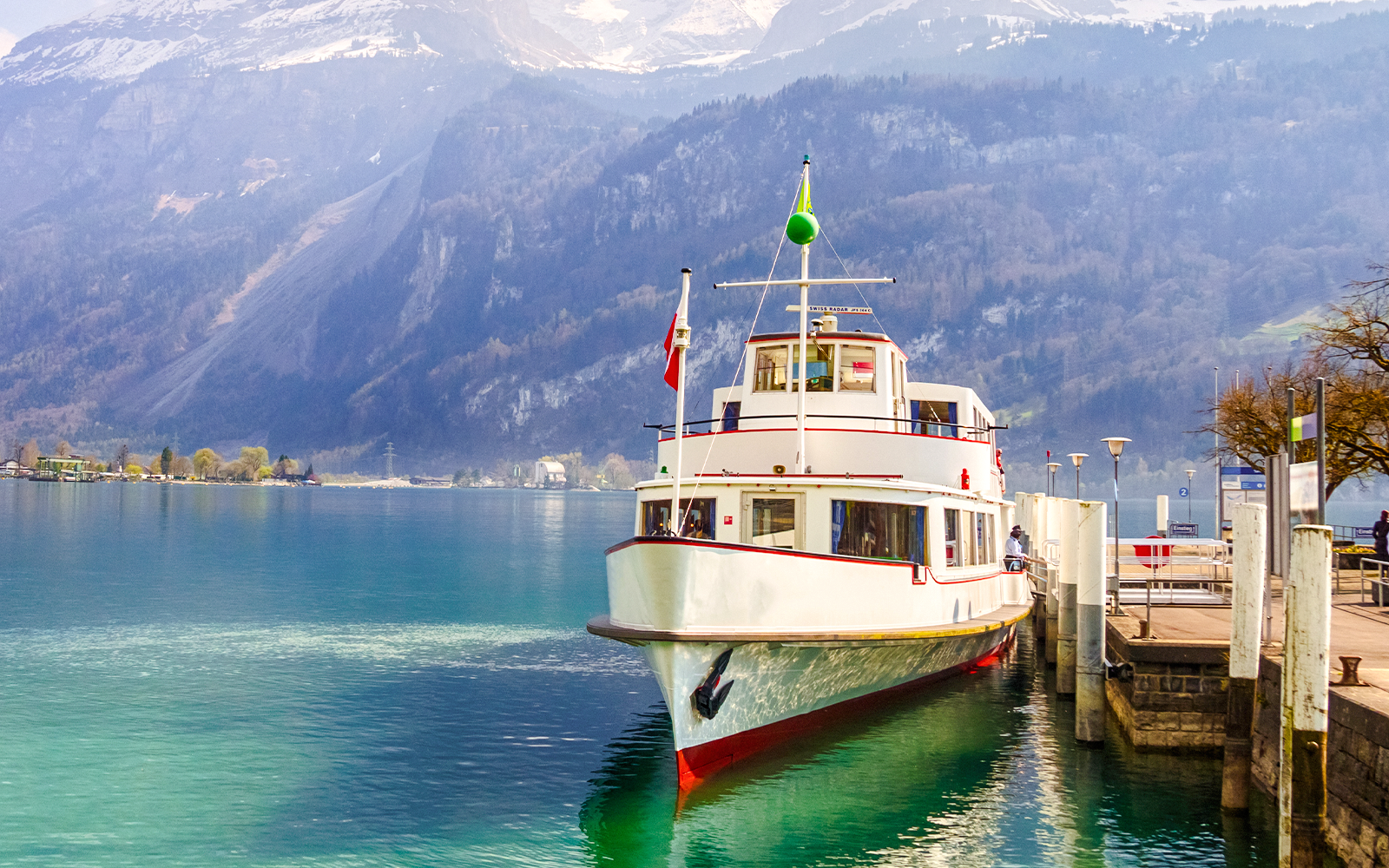 Tour boat docked at Brienz Lake port, Interlaken, Switzerland, with mountains in the background.