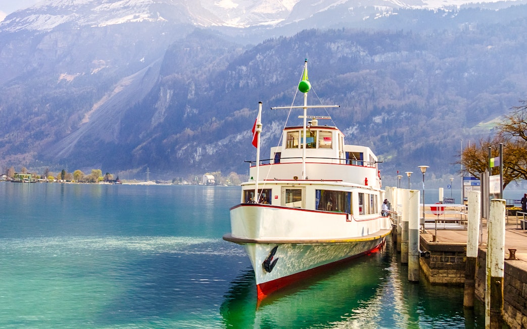Tour boat docked at Brienz Lake port, Interlaken, Switzerland, with mountains in the background.