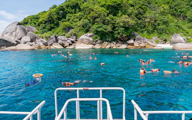 Snorkelers in clear blue water near rocky shore on Similan Islands day trip from Phuket.