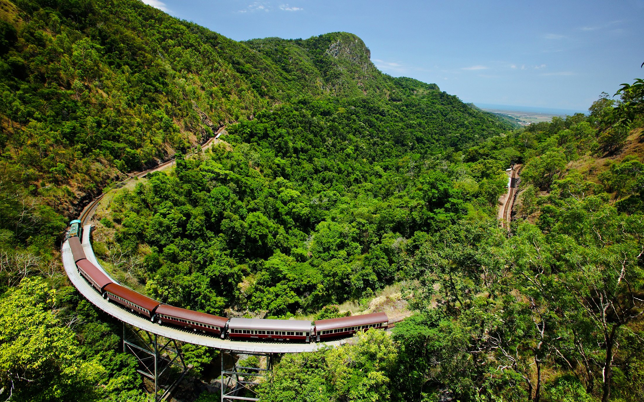 Scenic train crossing a lush green valley on a guided tour with transfers.
