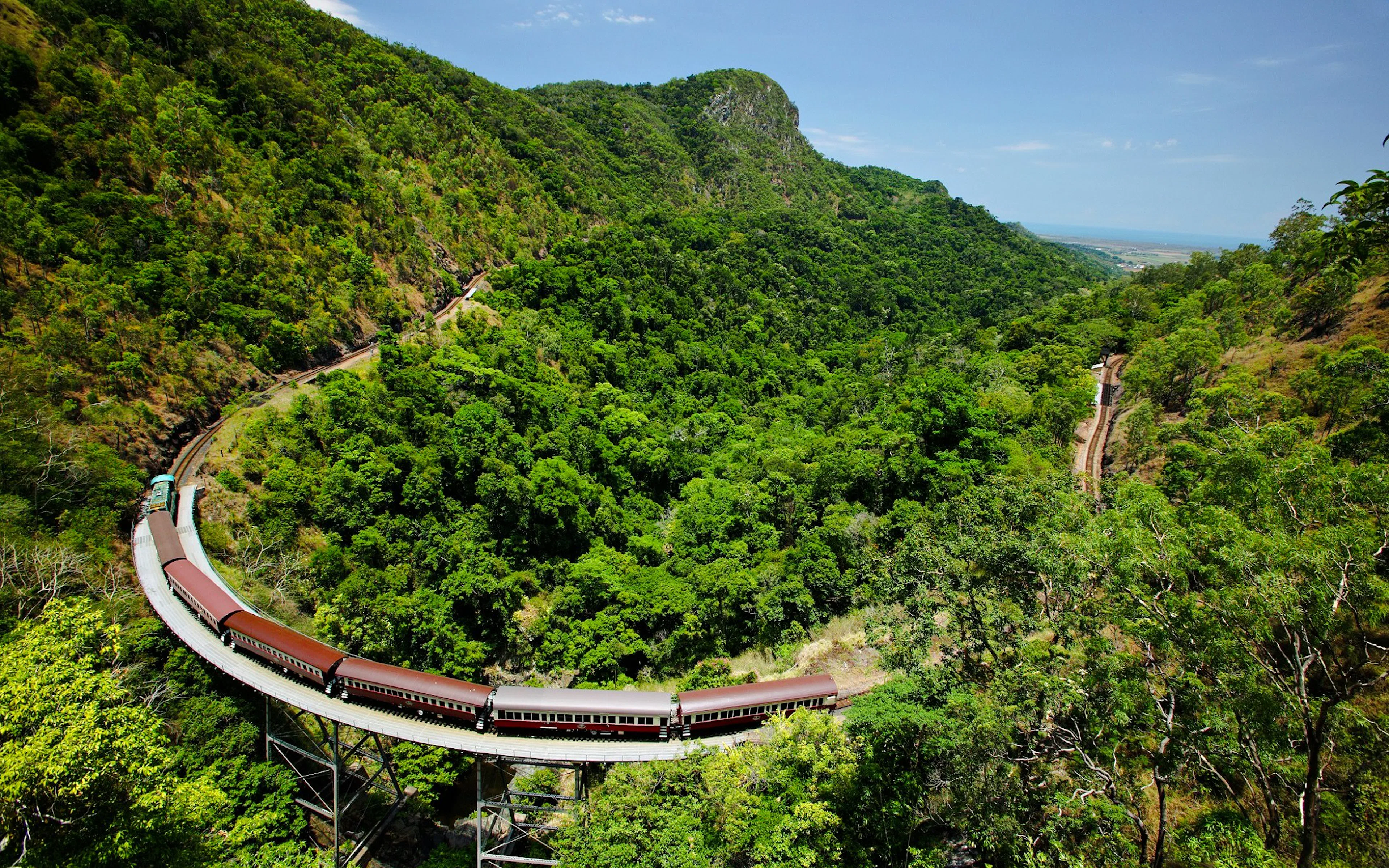 Scenic train crossing a lush green valley on a guided tour with transfers.
