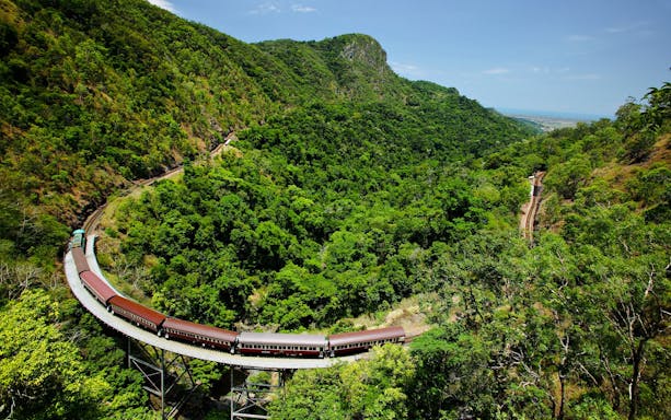 Scenic train crossing a lush green valley on a guided tour with transfers.