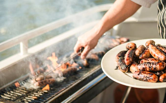 Grilling sausages on a barbecue during a lunch cruise in Mauritius.