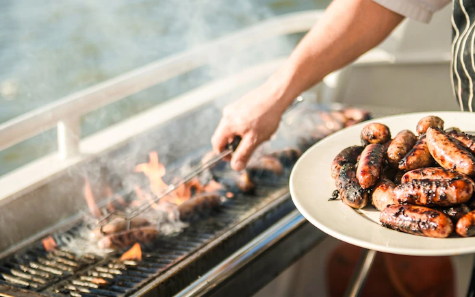 Grilling sausages on a barbecue during a lunch cruise in Mauritius.