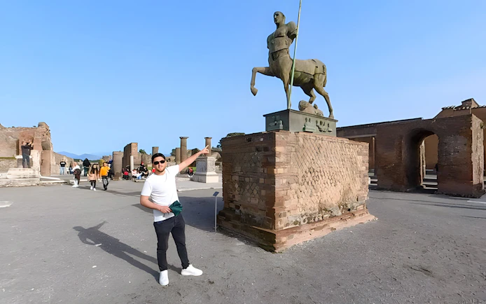 Tourists exploring the ancient ruins and centaur statue at Pompeii, Italy.