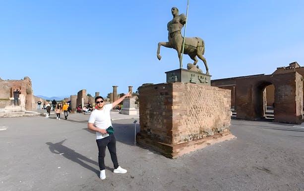 Tourists exploring the ancient ruins and centaur statue at Pompeii, Italy.