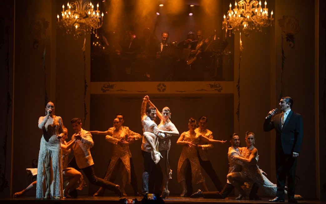 Tango dancers performing at Café de los Angelitos with live musicians in Buenos Aires.