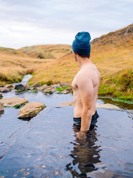Person enjoying the warm waters of the Secret Lagoon in Iceland's scenic landscape.