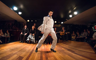 Flamenco dancer performing at Tablao LAS CARBONERAS in Madrid with musicians and audience.