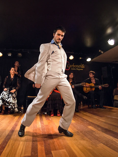 Flamenco dancer performing at Tablao LAS CARBONERAS in Madrid with musicians and audience.