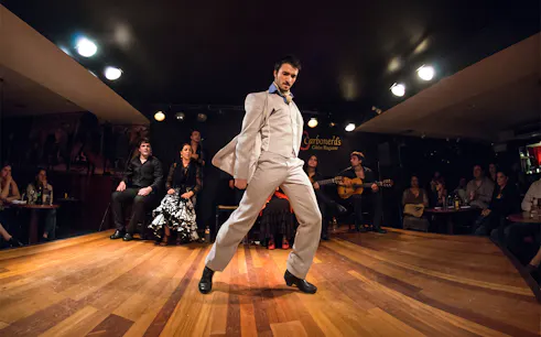 Flamenco dancer performing at Tablao LAS CARBONERAS in Madrid with musicians and audience.