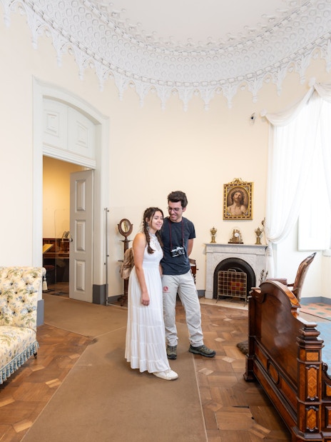 Tourist with guide in the Queen's bedroom of Pena Palace, Sintra, Portugal.