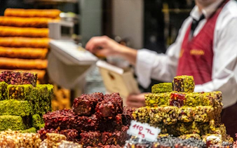 Turkish delight assortment at a shop in Istanbul, Turkey, with a vendor in the background.