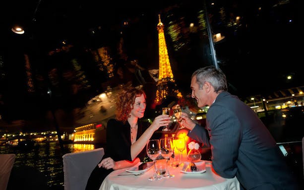 Couple toasting on a Valentine's Day dinner cruise with Eiffel Tower view.