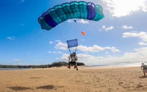 Tandem skydive landing on Sunshine Coast beach with parachute open.