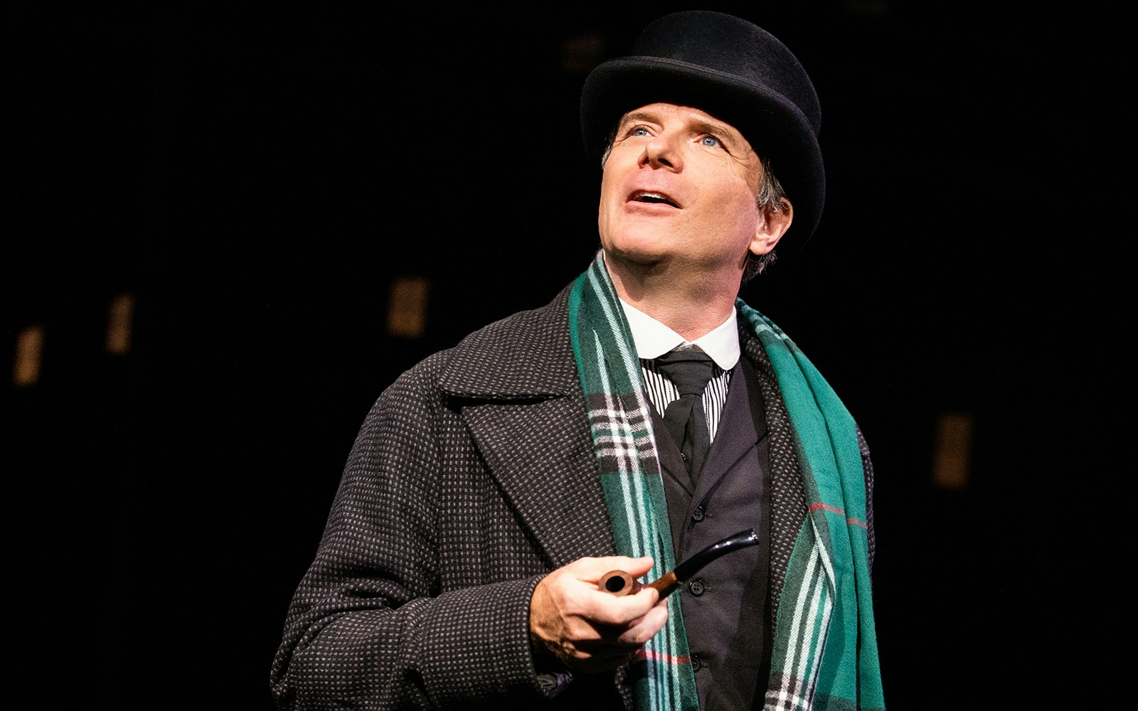 Man in Victorian attire holding a pipe, related to "A Sherlock Carol" performance.