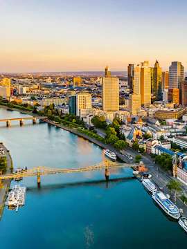 Frankfurt am Main skyline with river and bridge at sunset.