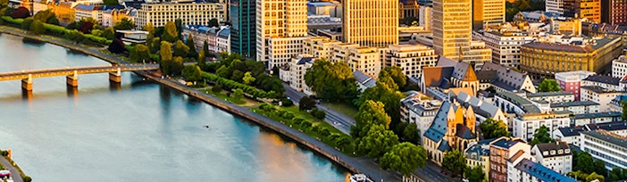 Frankfurt am Main skyline with river and bridge at sunset.