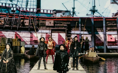 Historical reenactment with actors in period costumes on a dock, ship in the background, Willem van Oranje theme.