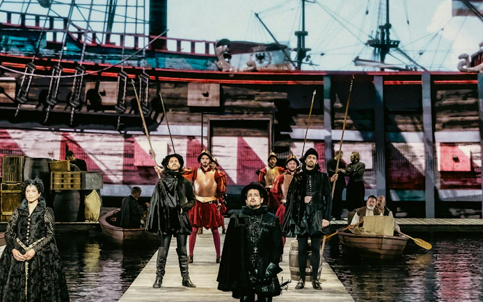 Historical reenactment with actors in period costumes on a dock, ship in the background, Willem van Oranje theme.