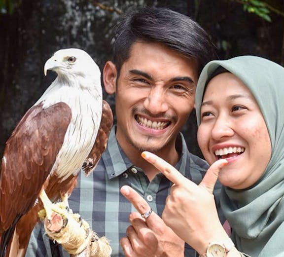 Couple smiling with a Brahminy Kite at Langkawi Wildlife Park.