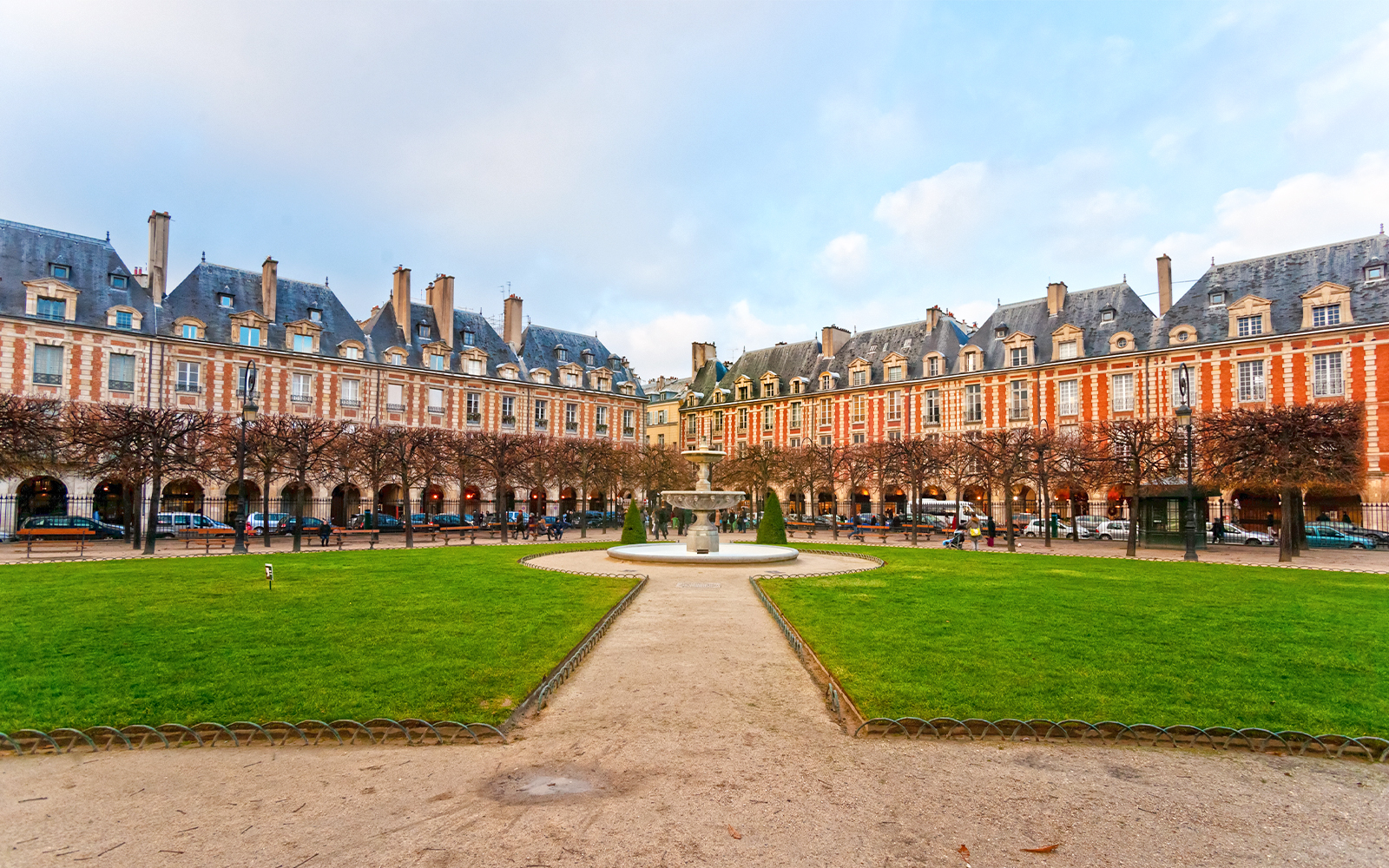 Place des Vosges courtyard with fountain and historic buildings in Paris, France.