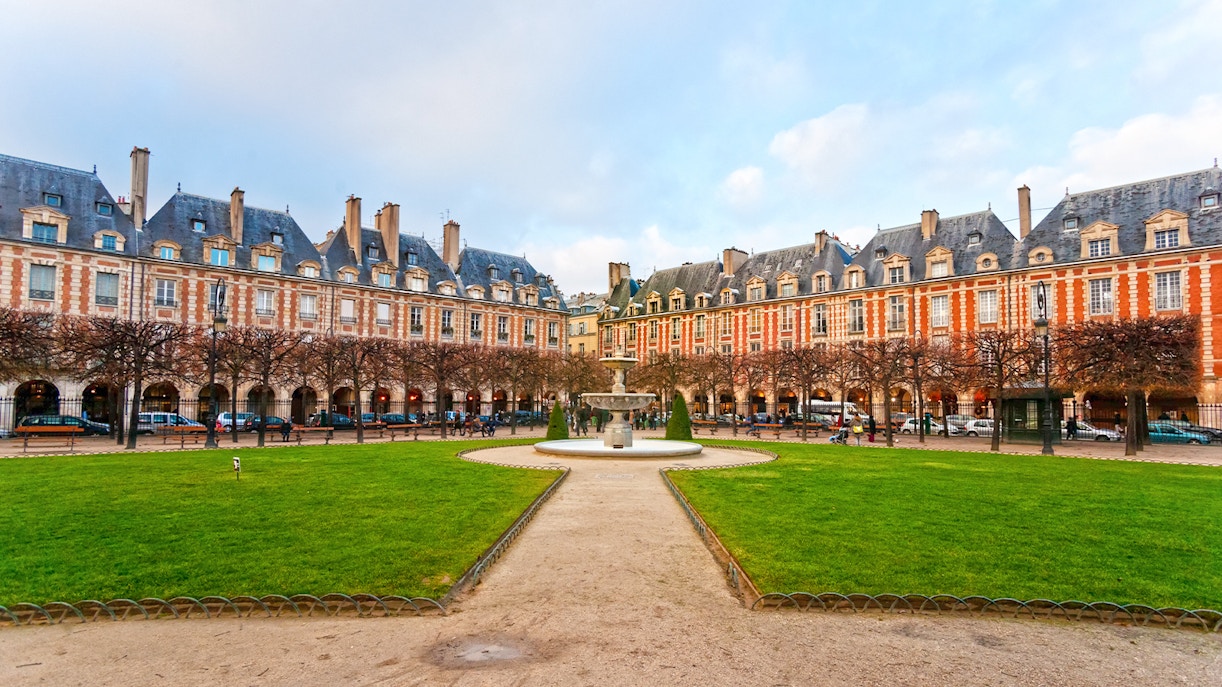 Place des Vosges courtyard with fountain and historic buildings in Paris, France.