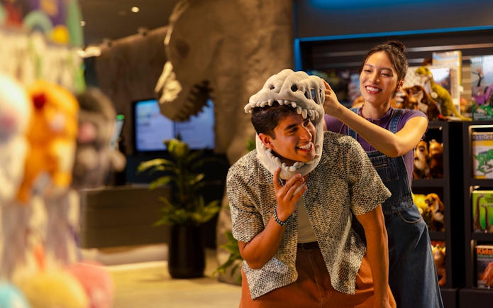 Man trying on dinosaur hat at Exploria gift shop, Mandai Wildlife.
