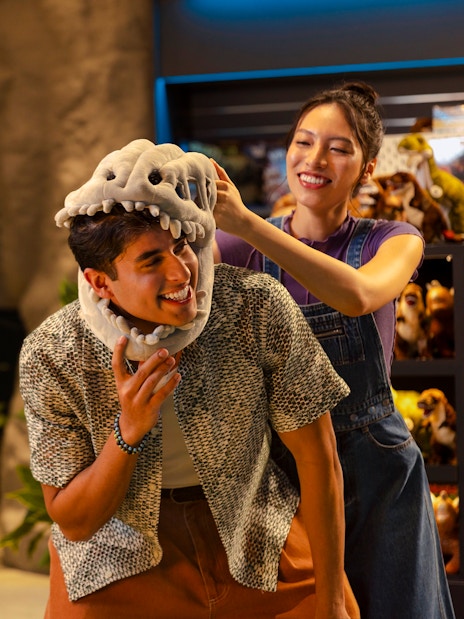 Man trying on dinosaur hat at Exploria gift shop, Mandai Wildlife.