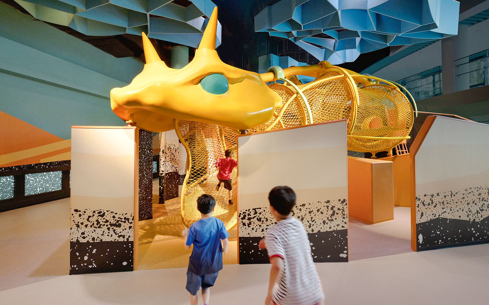 Children exploring giant snake structure at Curiosity Cove Dryland exhibit.