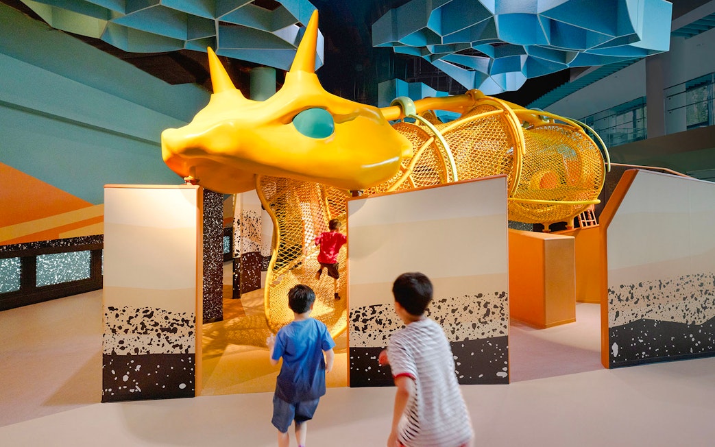 Children exploring giant snake structure at Curiosity Cove Dryland exhibit.