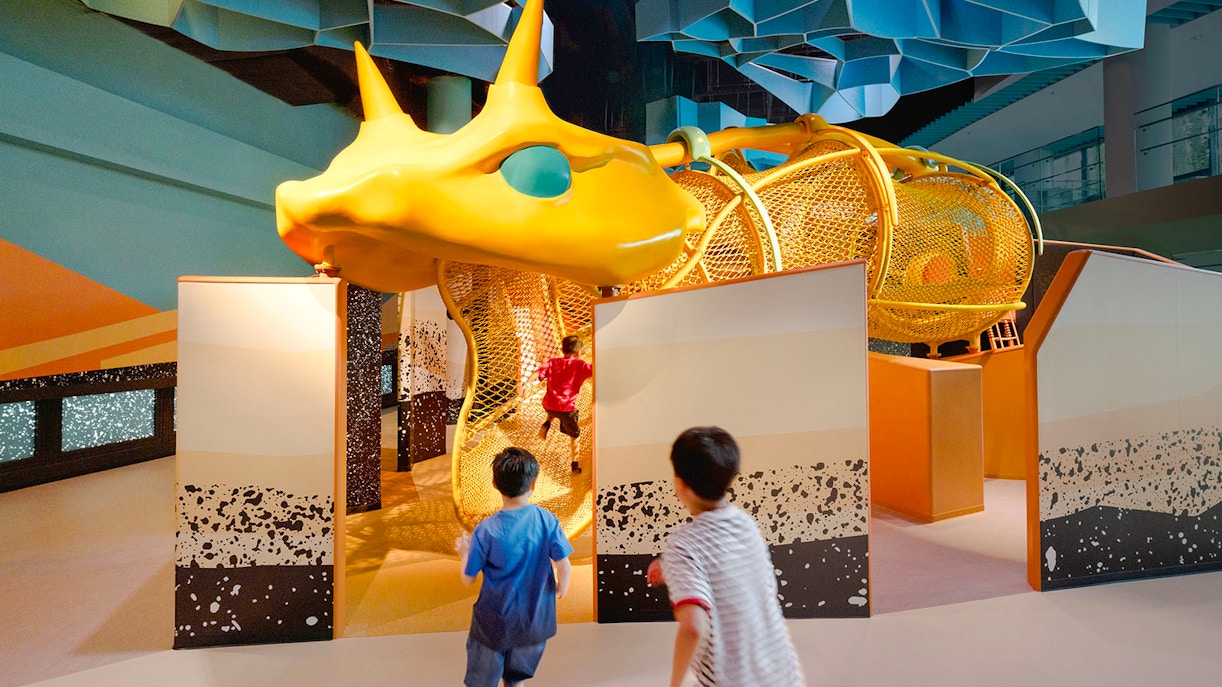 Children exploring giant snake structure at Curiosity Cove Dryland exhibit.