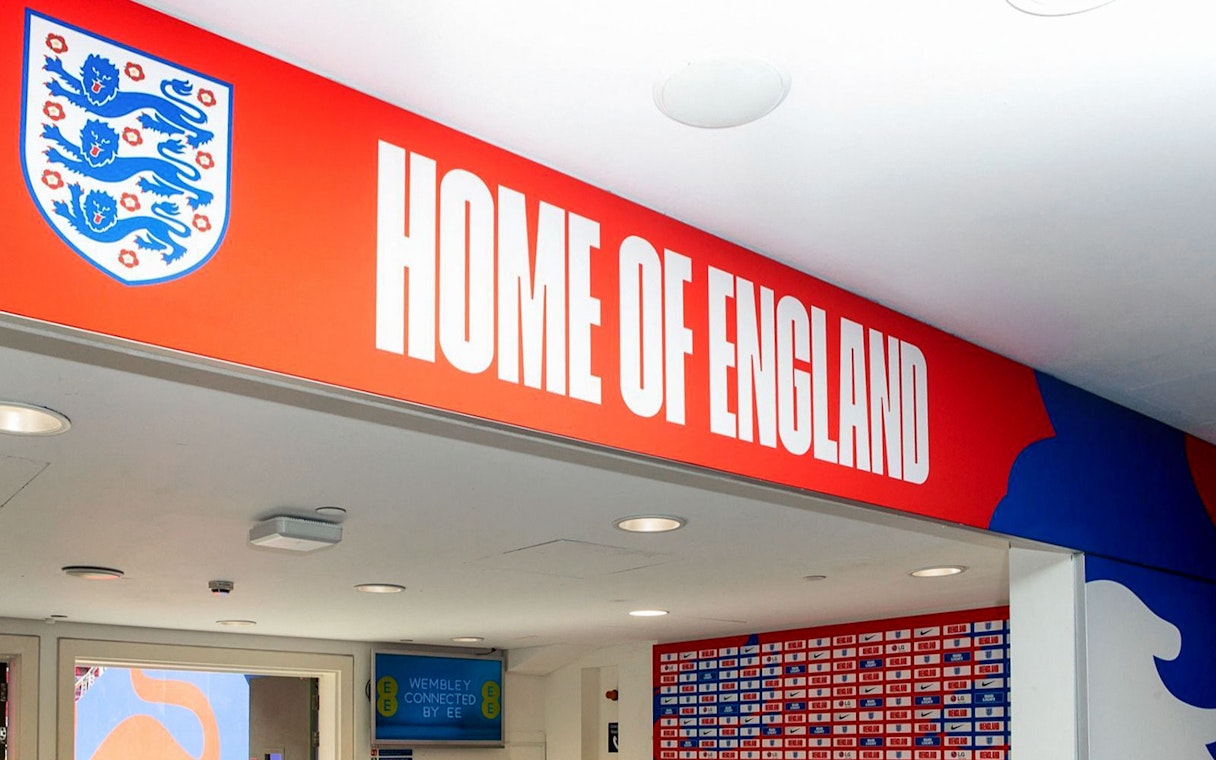 Player tunnel entrance at Wembley Stadium with "Home of England" sign.