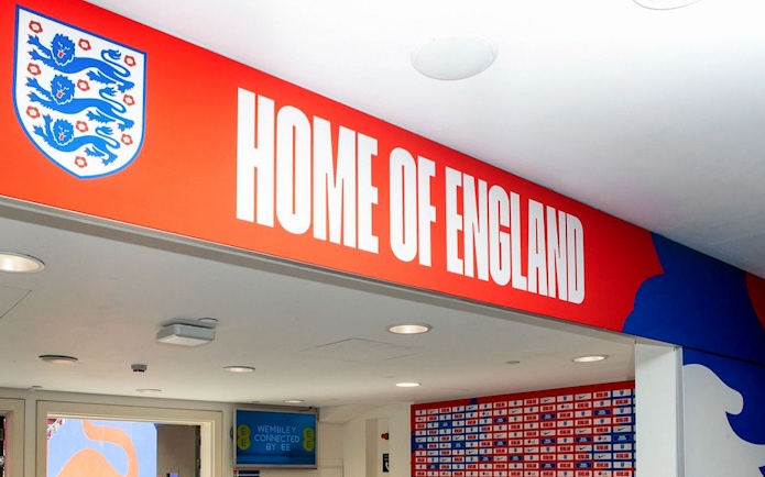 Player tunnel entrance at Wembley Stadium with "Home of England" sign.