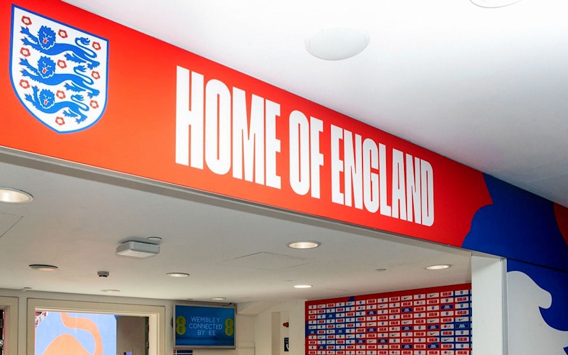 Player tunnel entrance at Wembley Stadium with "Home of England" sign.