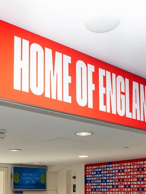 Player tunnel entrance at Wembley Stadium with "Home of England" sign.