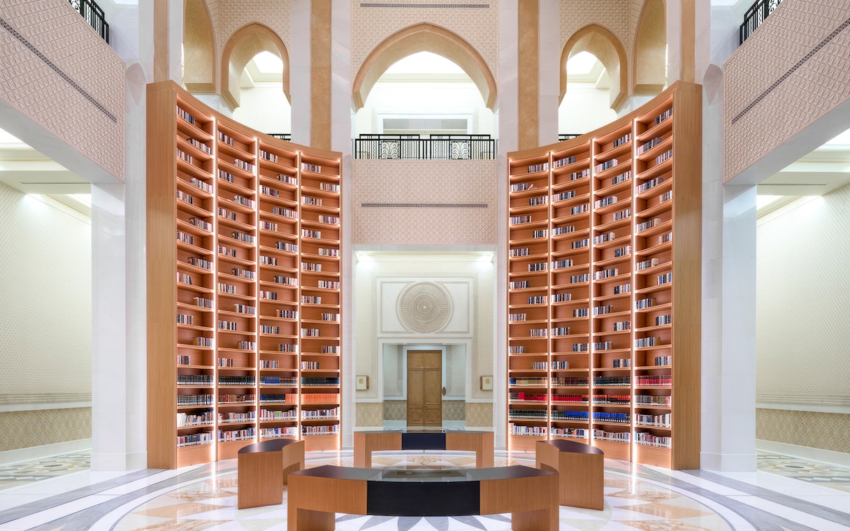 Qasr Al Watan Library interior with tall wooden bookshelves and arched architecture.