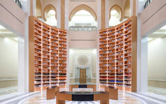 Qasr Al Watan Library interior with tall wooden bookshelves and arched architecture.