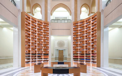 Qasr Al Watan Library interior with tall wooden bookshelves and arched architecture.
