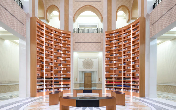 Qasr Al Watan Library interior with tall wooden bookshelves and arched architecture.