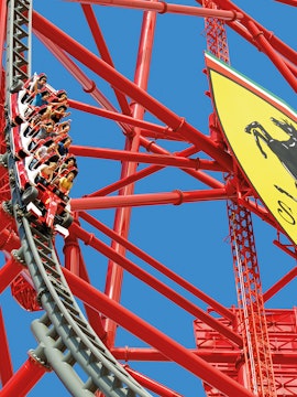 Roller coaster at Ferrari Land with riders on a steep descent.