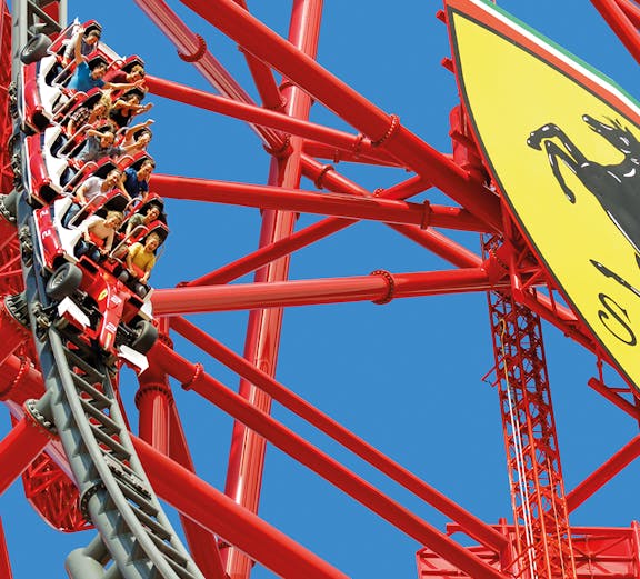 Roller coaster at Ferrari Land with riders on a steep descent.