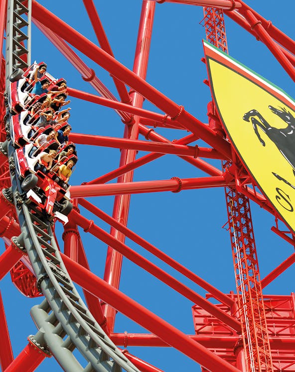 Roller coaster at Ferrari Land with riders on a steep descent.
