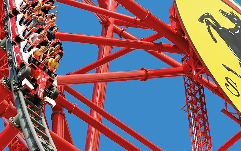 Roller coaster at Ferrari Land with riders on a steep descent.