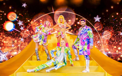 Performers in colorful costumes on stage at Friedrichstadt Palast, Berlin.