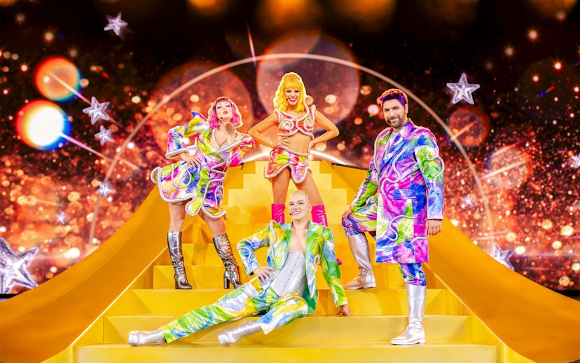 Performers in colorful costumes on stage at Friedrichstadt Palast, Berlin.