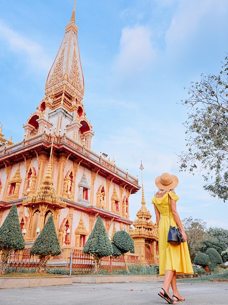 Woman in yellow dress visiting Wat Chalong temple in Phuket on a guided tour.
