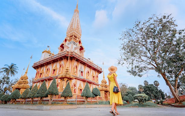 Woman in yellow dress visiting Wat Chalong temple in Phuket on a guided tour.
