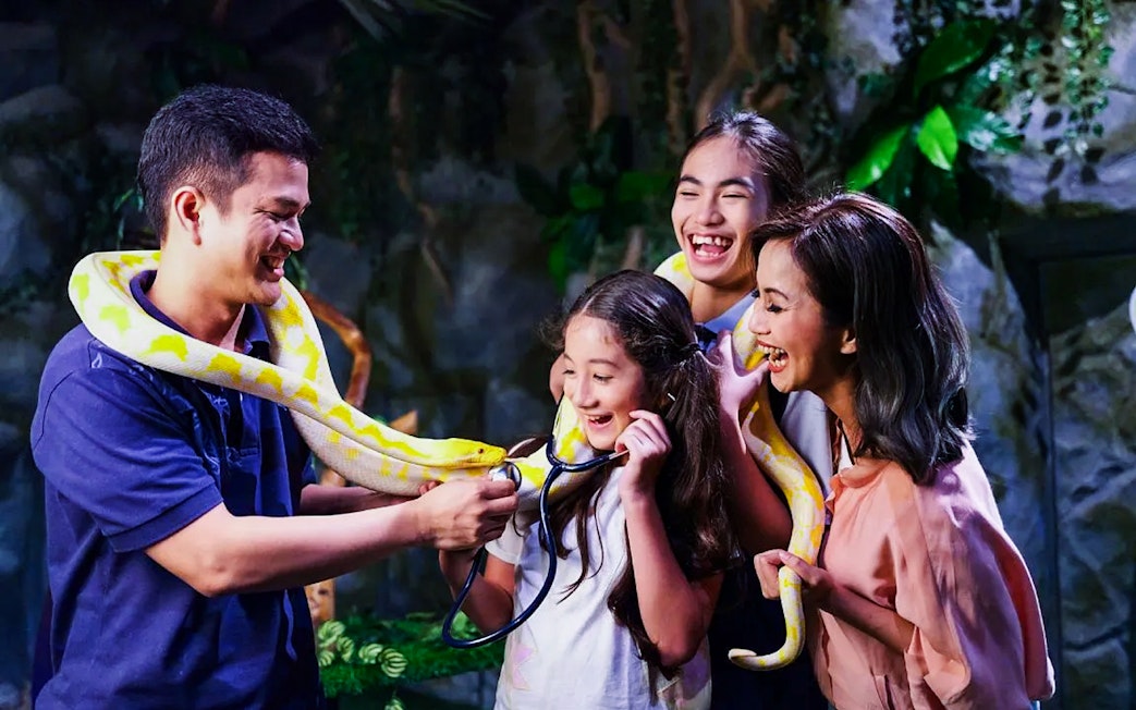 Tourists interacting with a snake at Jakarta Aquarium Safari.